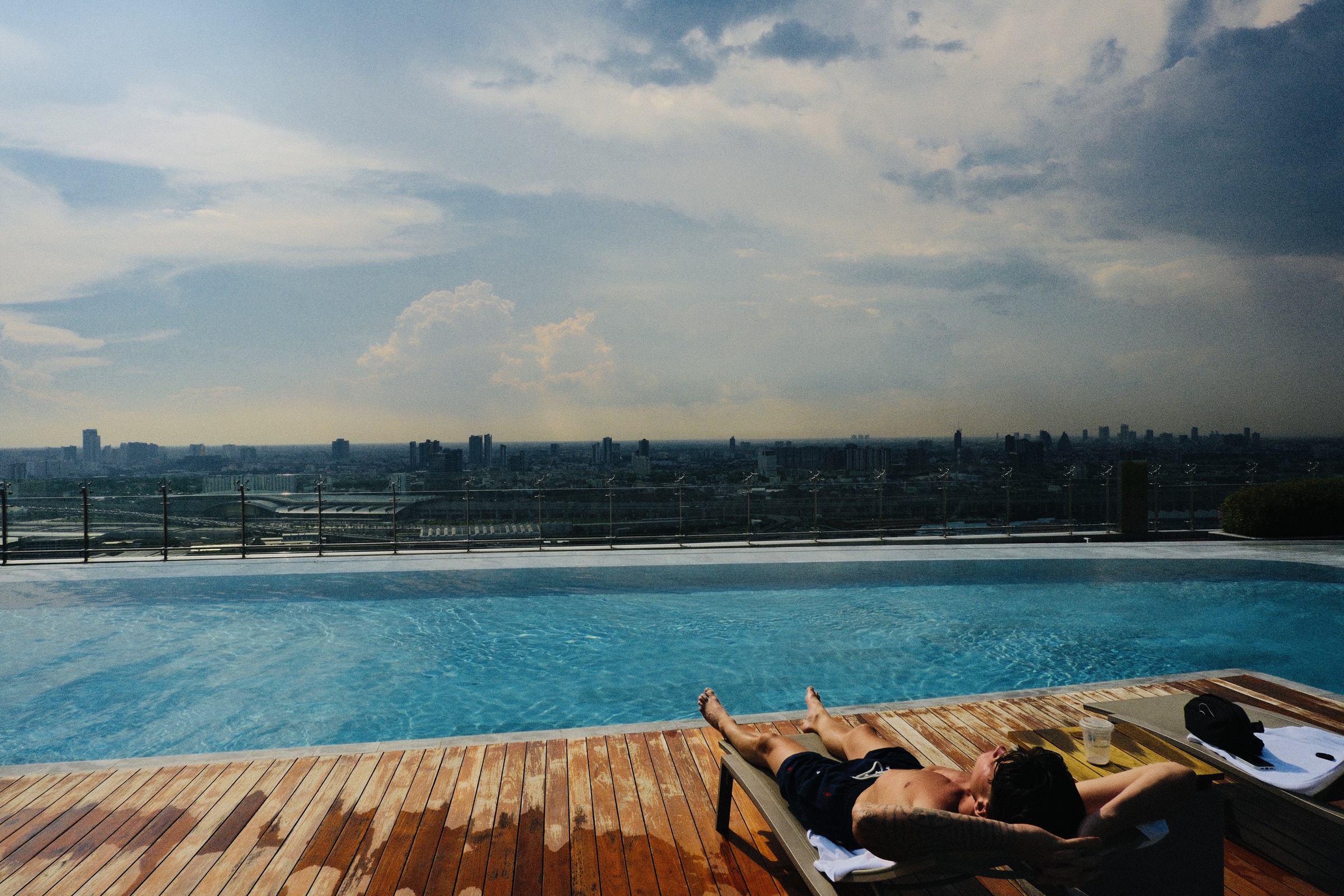 Freddie relaxing beside a rooftop pool overlooking the city